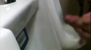 two slim dicks getting wanked at the urinals