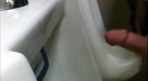 two slim dicks getting wanked at the urinals