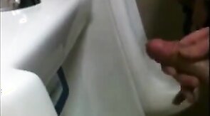 two slim dicks getting wanked at the urinals